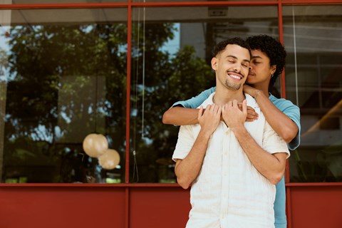 A couple is hugging each other in front of a window.