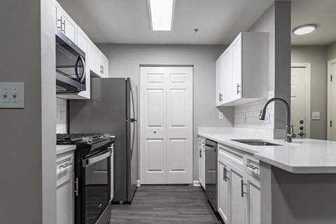 kitchen with stainless steel appliances and white cabinets at Ellington Metro West apartments