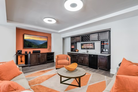 A living room with orange chairs and a television.