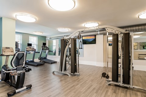 A gym with a variety of equipment including treadmills, stationary bikes, and weight machines.