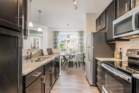 A modern kitchen with dark wood floors and stainless steel appliances.