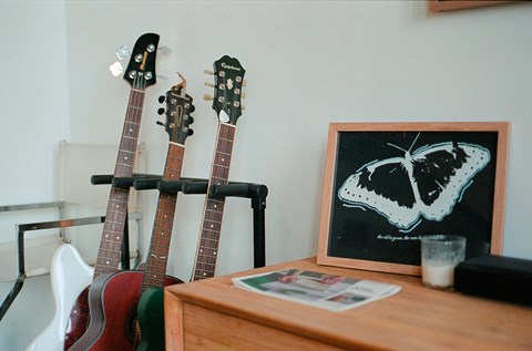 Three guitars are leaning against a wall on a stand.