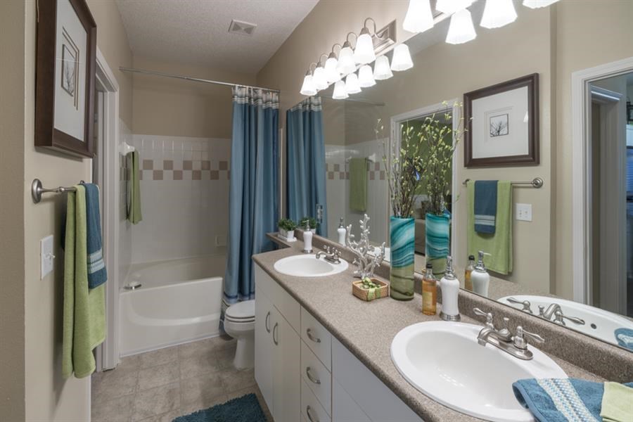 Master bathroom with floating vanities, quartz countertops, backlit vanity mirror, walk-in shower with Euro shower door and quartz-topped bench seat at Wyndchase  Aspen Grove, Tennessee, 37067