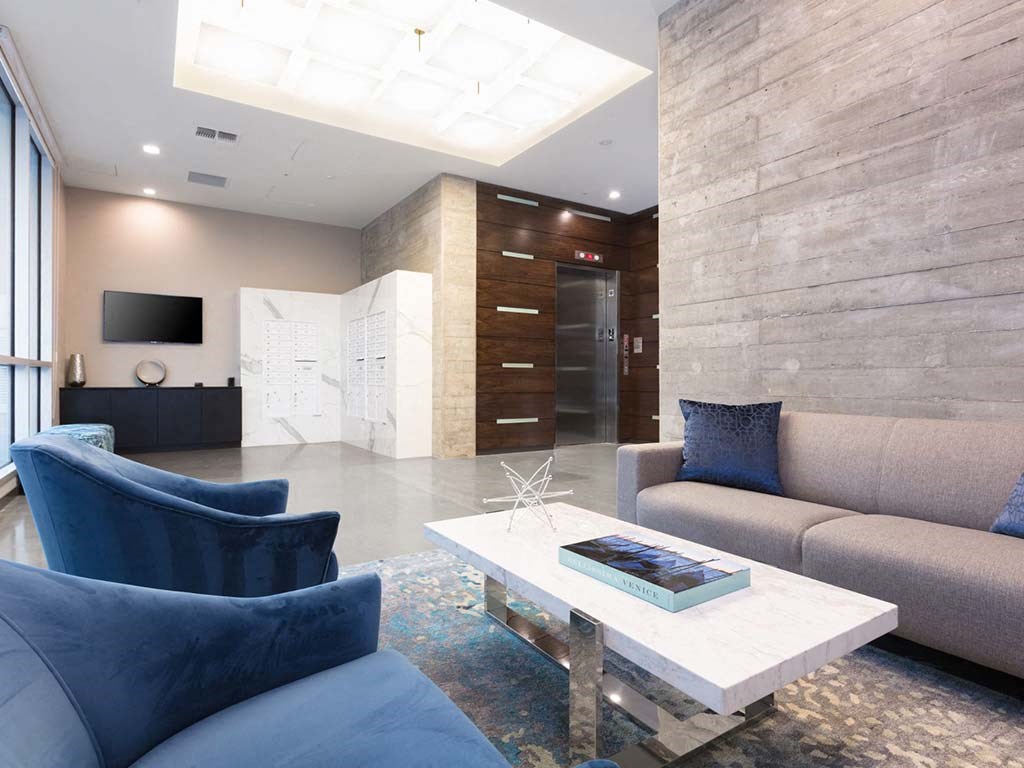 Indoor common area with blue armchairs and grey sofa at Lyric, Walnut Creek, CA
