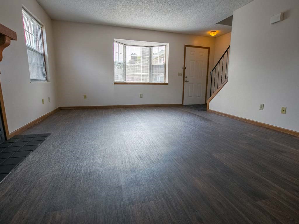an empty living room with wood floors and a window