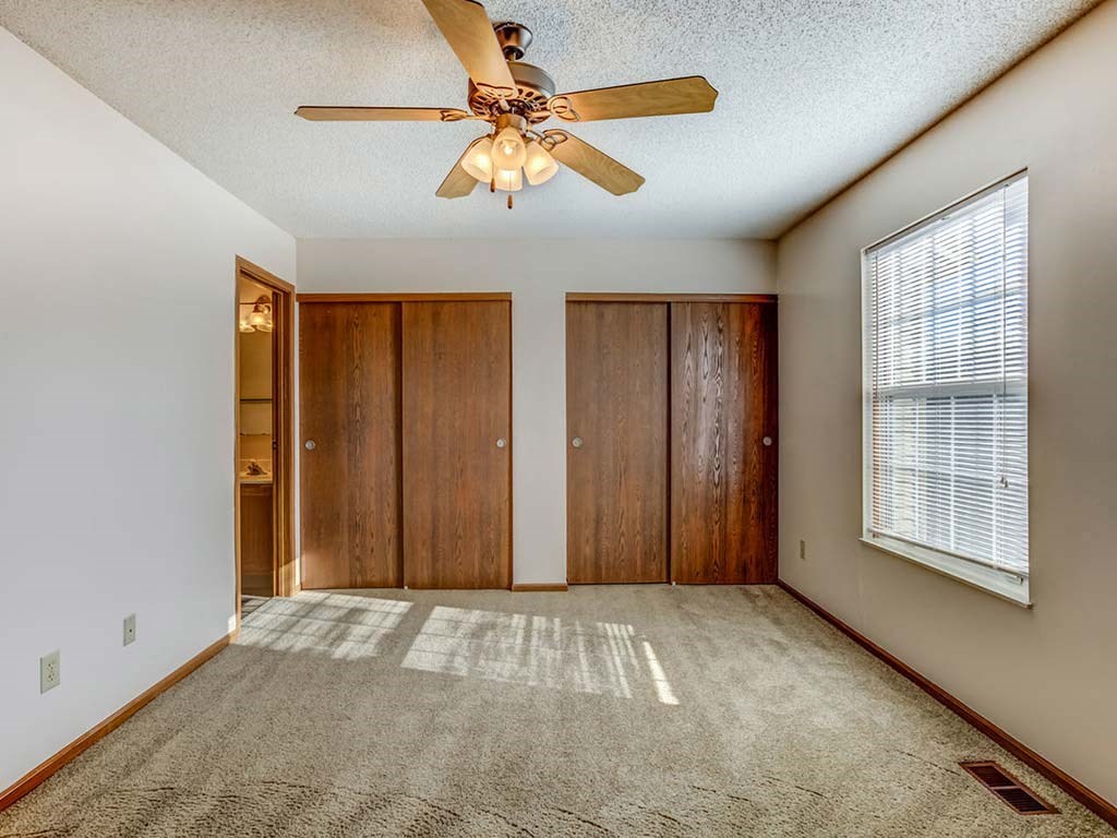 A room with a ceiling fan and carpeted floor.