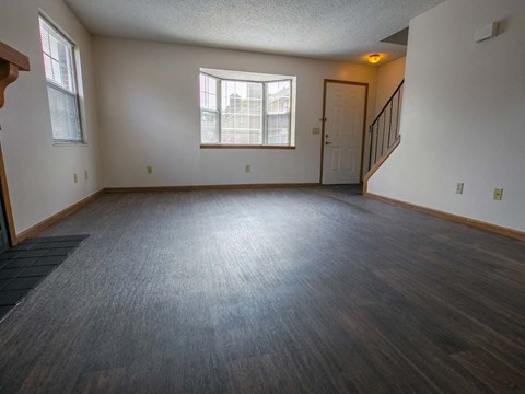 A room with a wooden floor and a staircase.