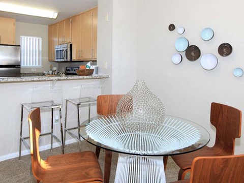 a dining area with a table and chairs and a kitchen in the background