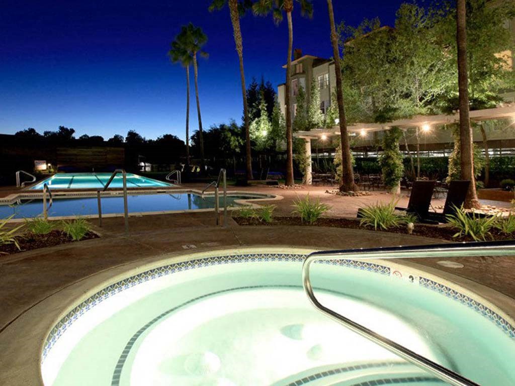 a pool at night with a hotel in the background