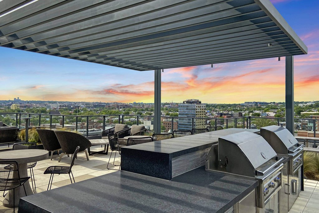 a rooftop terrace with a grill and a view of the city at sunset at Tribeca NOMA apartments