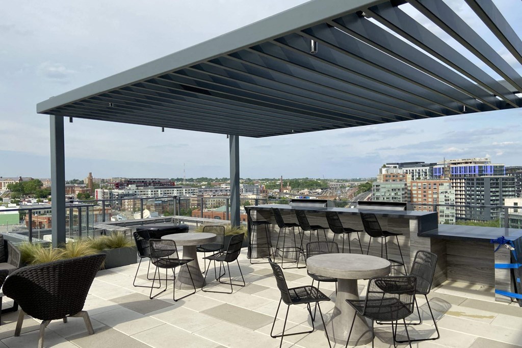 a rooftop patio with tables and chairs and a view of the city at Tribeca NOMA apartments