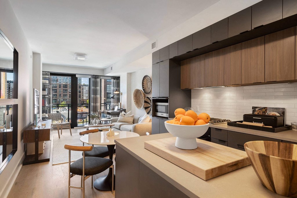 a kitchen with wooden cabinets and a living room in Tribeca NOMA apartments