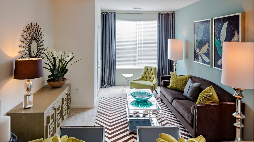 a living room with a couch and table and large window at Reveal Hackensack apartments
