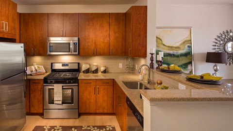 a kitchen with stainless steel appliances and wooden cabinets at Reveal Hackensack apartments