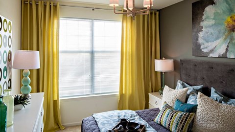 a bedroom with yellow curtains and a window at Reveal Hackensack apartments