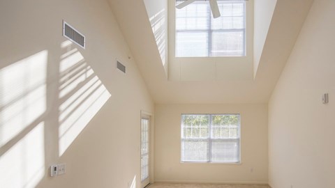 a living room with two windows and a high ceiling at Reveal Hackensack apartments