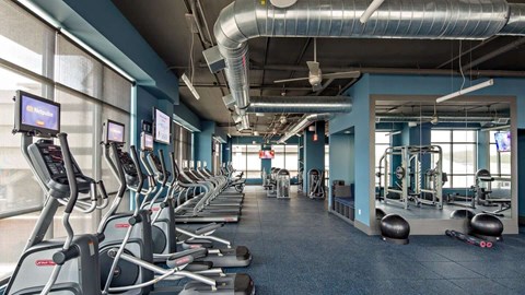 a gym with cardio equipment and weights in Reveal Hackensack apartments