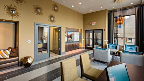 a lobby with tables and bright chairs at Reveal Hackensack apartments