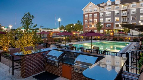 a grilling area and pool at Reveal Hackensack apartments in Hackensack New Jersey