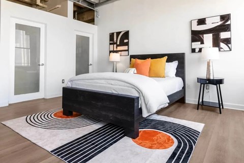 A bedroom with a large bed and a rug with a circular design.