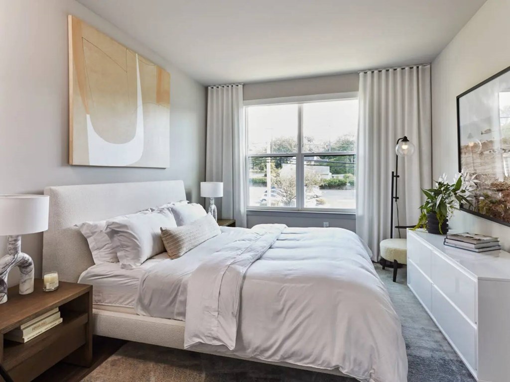 A bedroom with a large bed and a painting on the wall.