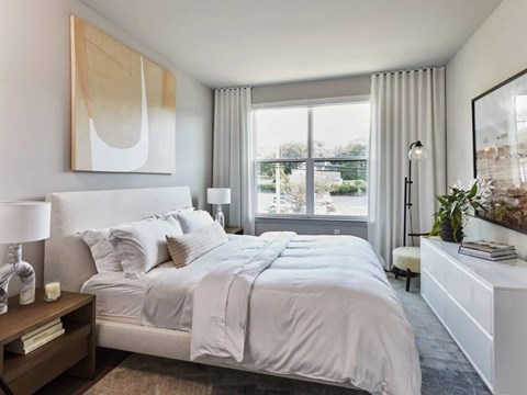 A bedroom with a large bed and a painting on the wall.