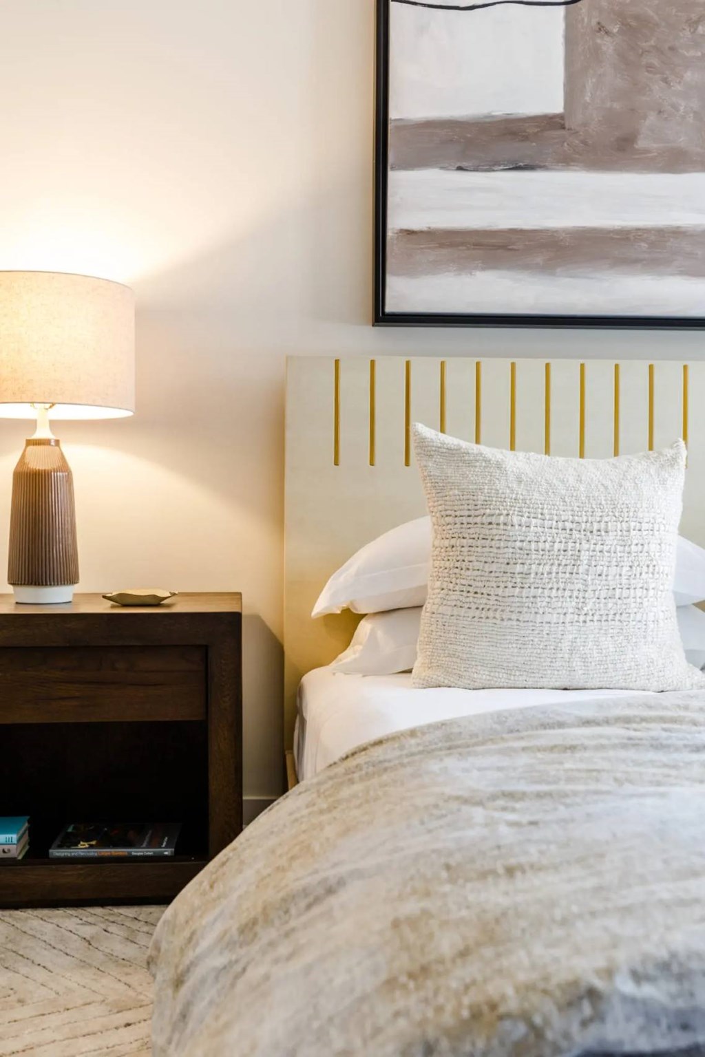 A bed with a white pillow and a lamp on a nightstand.