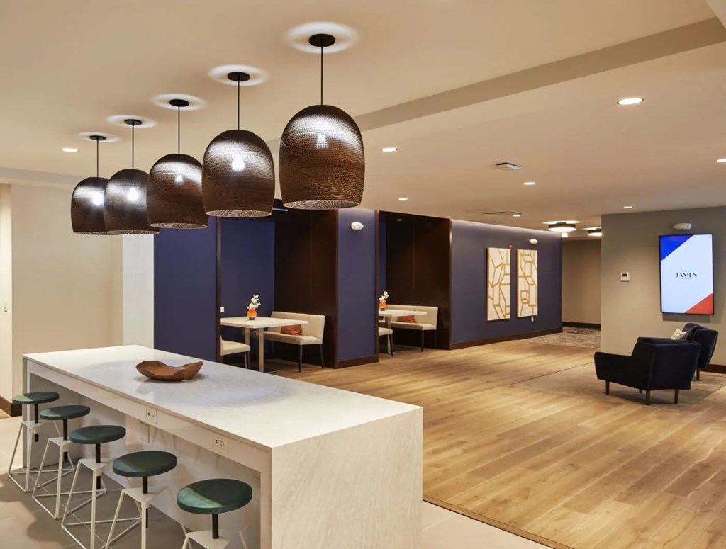 A modern kitchen with a white countertop and bar stools.