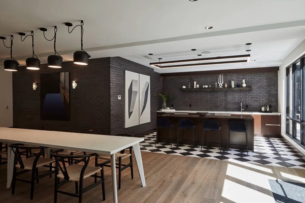 A modern kitchen with a long white table and chairs.