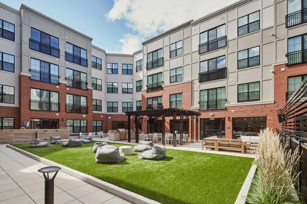 A courtyard with a grassy area and a pergola.