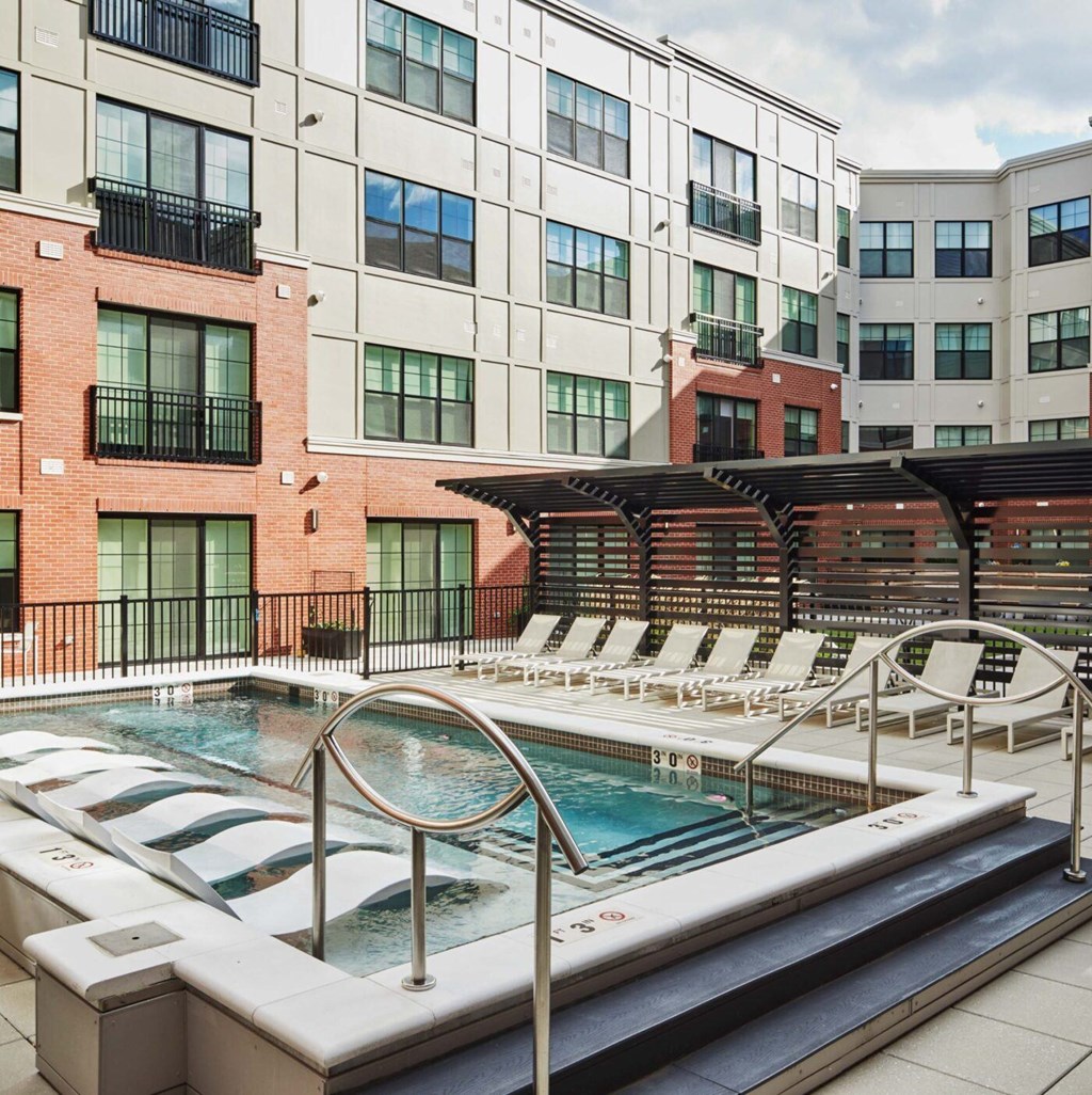 A pool with a hot tub in front of a building.