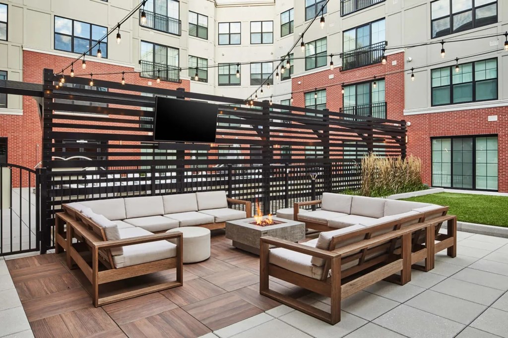 A patio with a wooden table and chairs and a TV mounted on a wall.