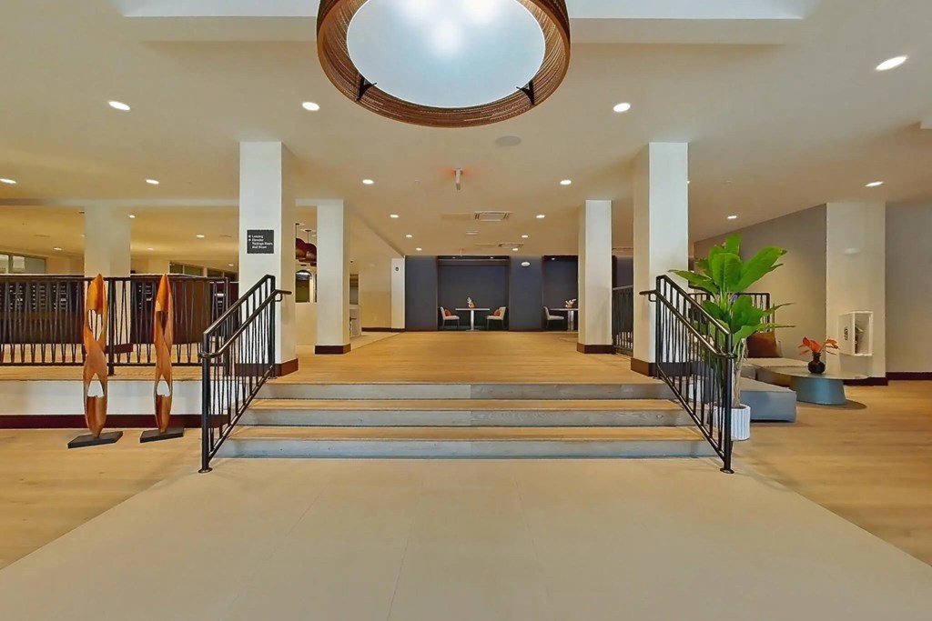 A large, open hallway with a staircase and a plant.