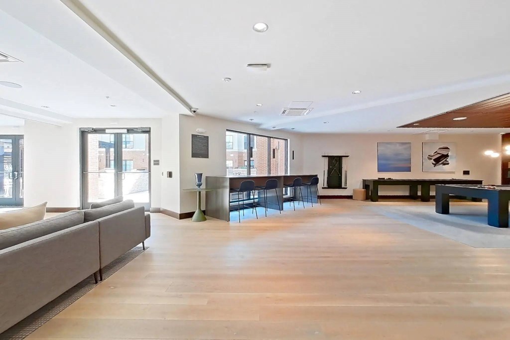 A spacious living room with a grey sofa and a wooden floor.