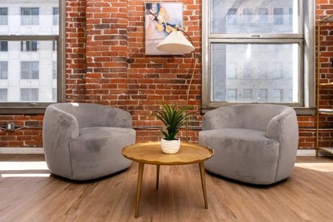 Two grey armchairs and a small table with a plant on it.