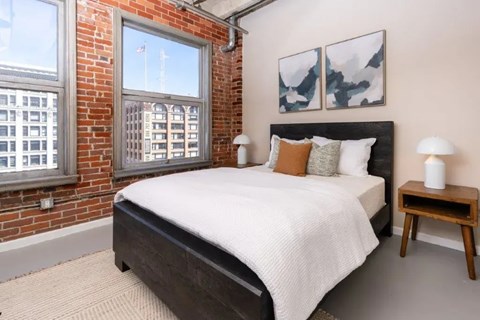 A bedroom with a large bed and a window overlooking a cityscape.
