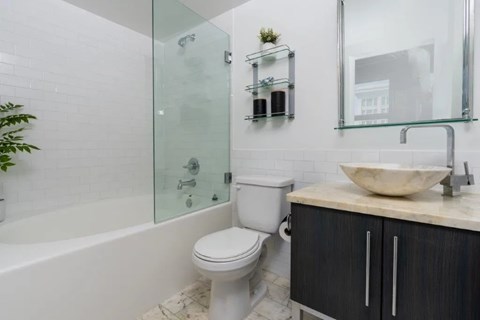 A bathroom with a white toilet, a sink, and a glass shower enclosure.