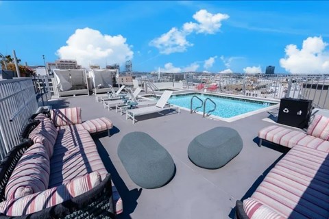 A rooftop patio with a pool, lounge chairs, and a view of the city.