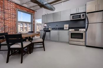 A kitchen with a brick wall and stainless steel appliances.
