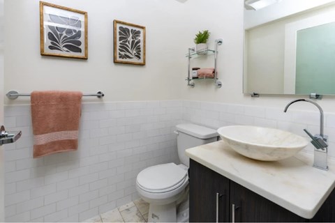 A bathroom with a toilet, sink, and two wall-mounted shelves.