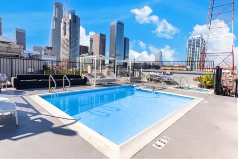 A swimming pool on a rooftop with a city skyline in the background.
