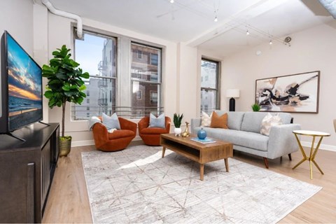 A living room with a grey couch, a wooden coffee table, and a large painting on the wall.