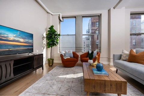 A living room with a large flat screen TV and a view of the city.