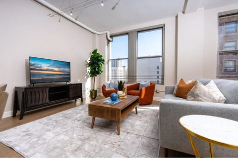 A living room with a grey couch, a wooden coffee table, and a large flat screen TV.
