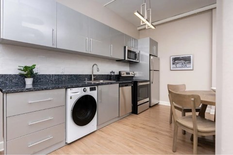 A modern kitchen with a washing machine and a microwave.