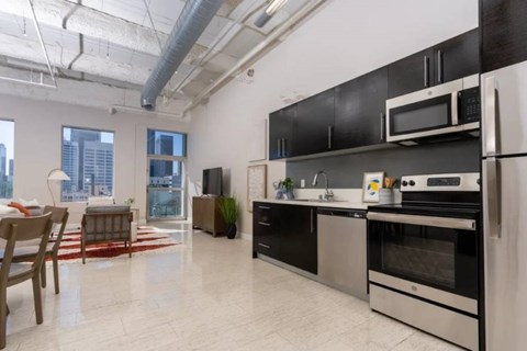 A kitchen with black cabinets and stainless steel appliances.