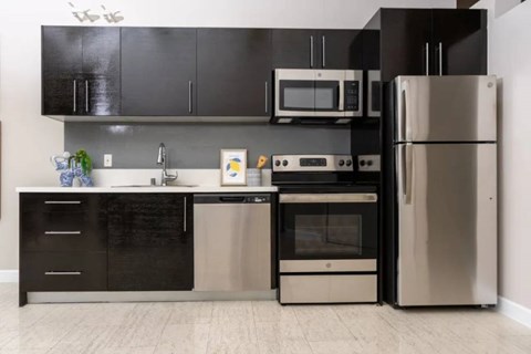 A modern kitchen with black cabinets and stainless steel appliances.