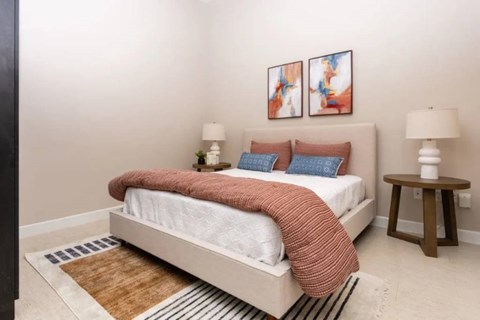 A bedroom with a white bed and a brown rug.