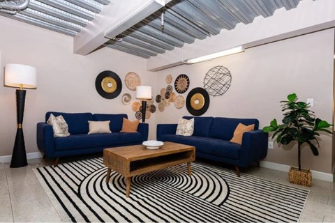 A living room with a blue couch, a wooden coffee table, and a striped rug.