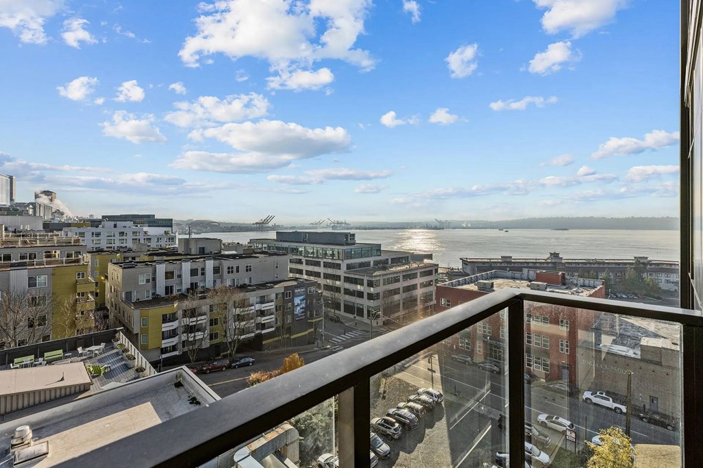 A balcony overlooks a cityscape with buildings and a body of water.